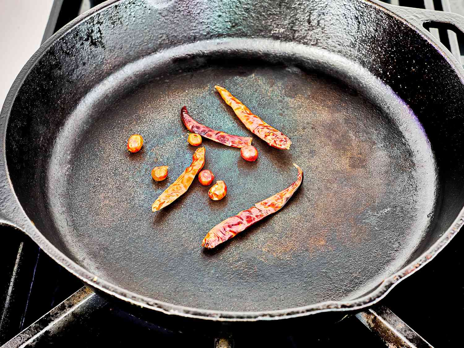Peppers being toasted in a cast iron skillet