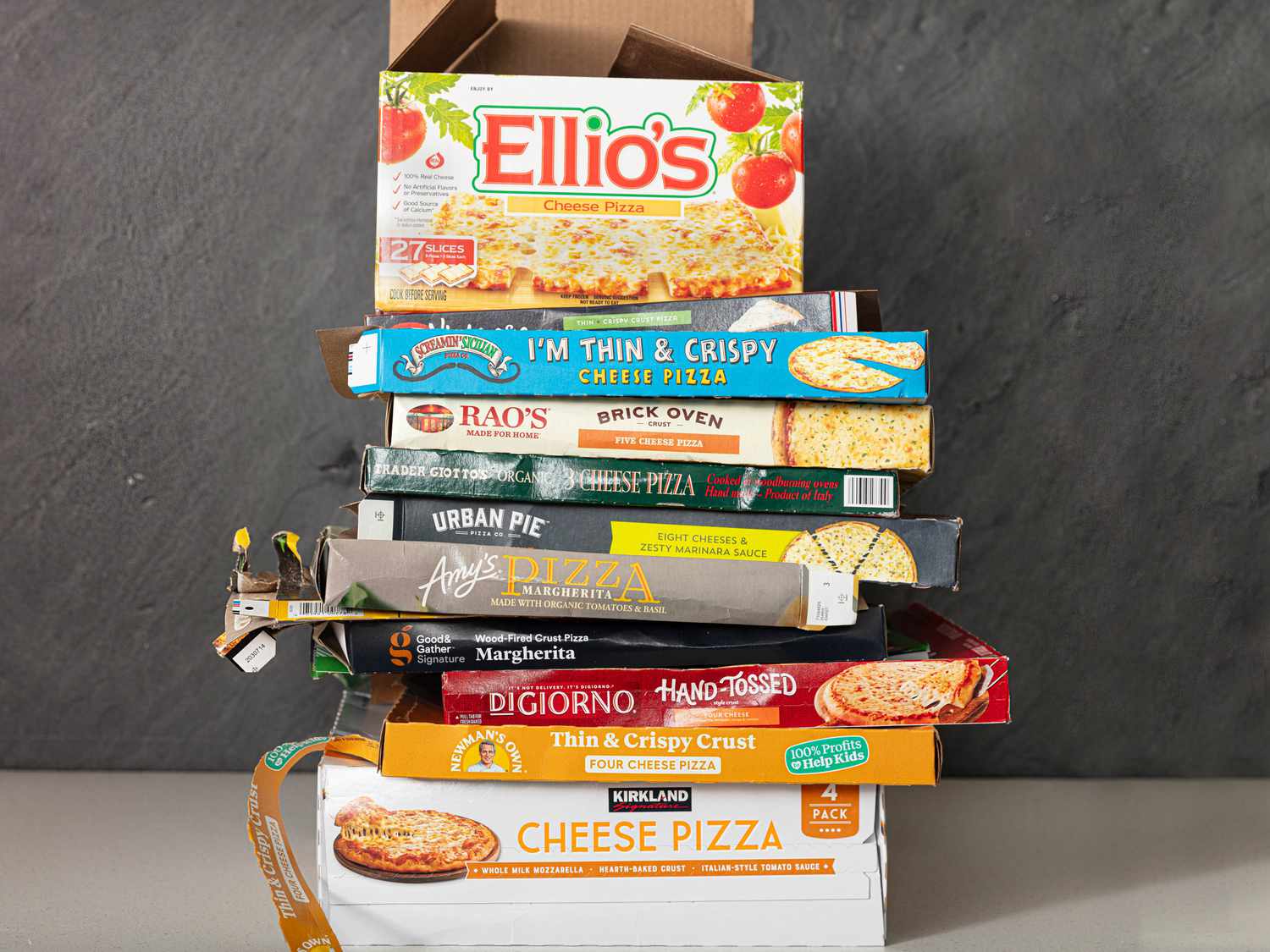 stack of different empty frozen pizza boxes on top of eachother 