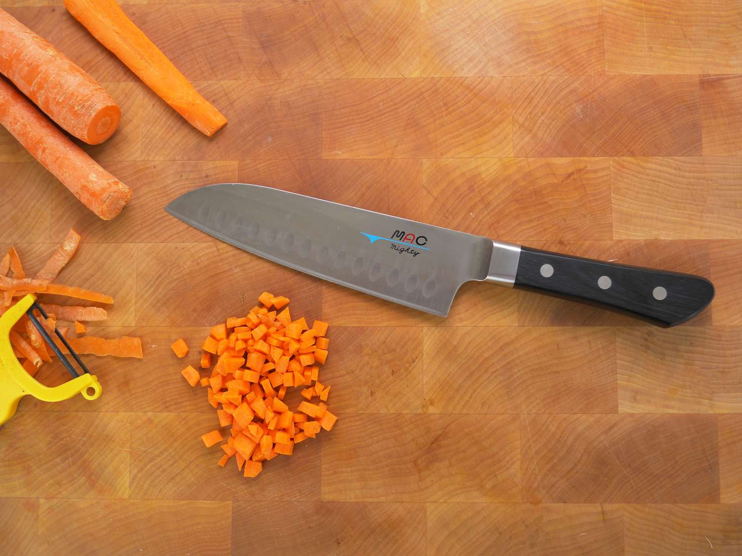 mac hollow edge santoku on a cutting board with cubed carrots