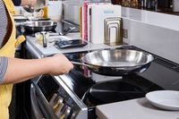 A person cooks with the Le Creuset 12 Inch Large Tri-Ply Stainless Steel Fry Pan