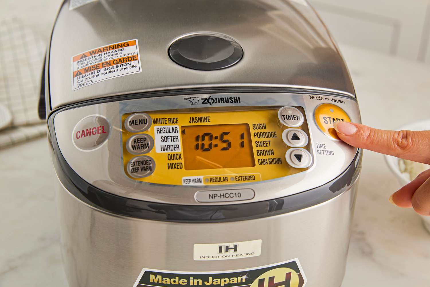 A person pressing start on the Zojirushi rice cooker.