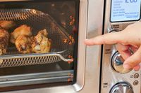 A finger pointing to chicken cooking in the Breville the Joule Oven Air Fryer Pro