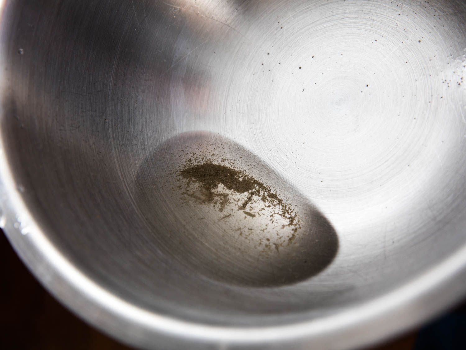 Sandy water in the bottom of a metal mixing bowl
