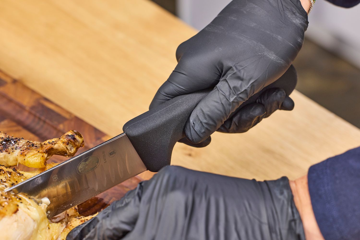 A person slices meat with the Victorinox Fibrox Pro 12-Inch Slicing Knife with Granton Blade