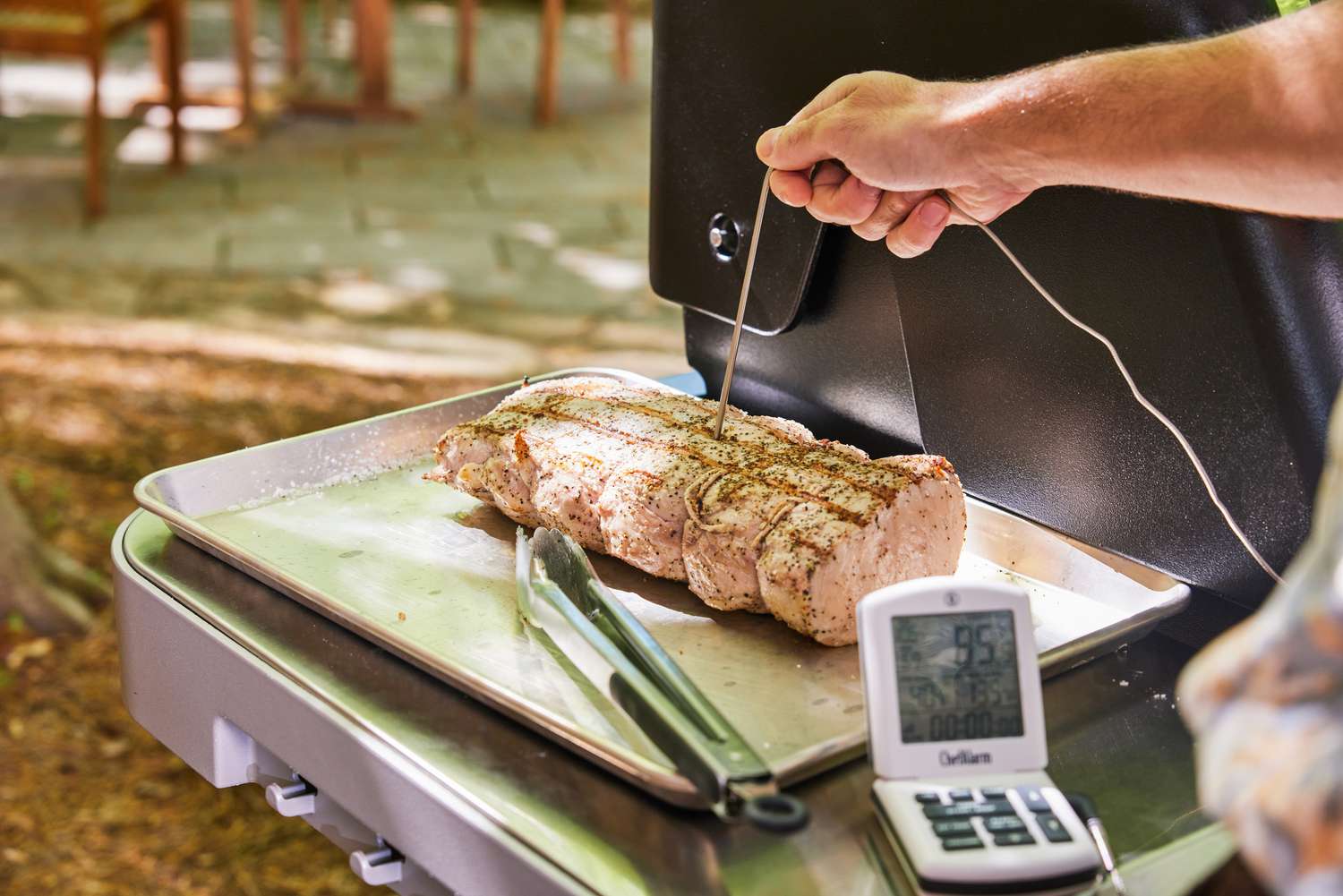 Hand inserting a probe into a piece of chicken connecting it to the ThermoWorks ChefAlarm