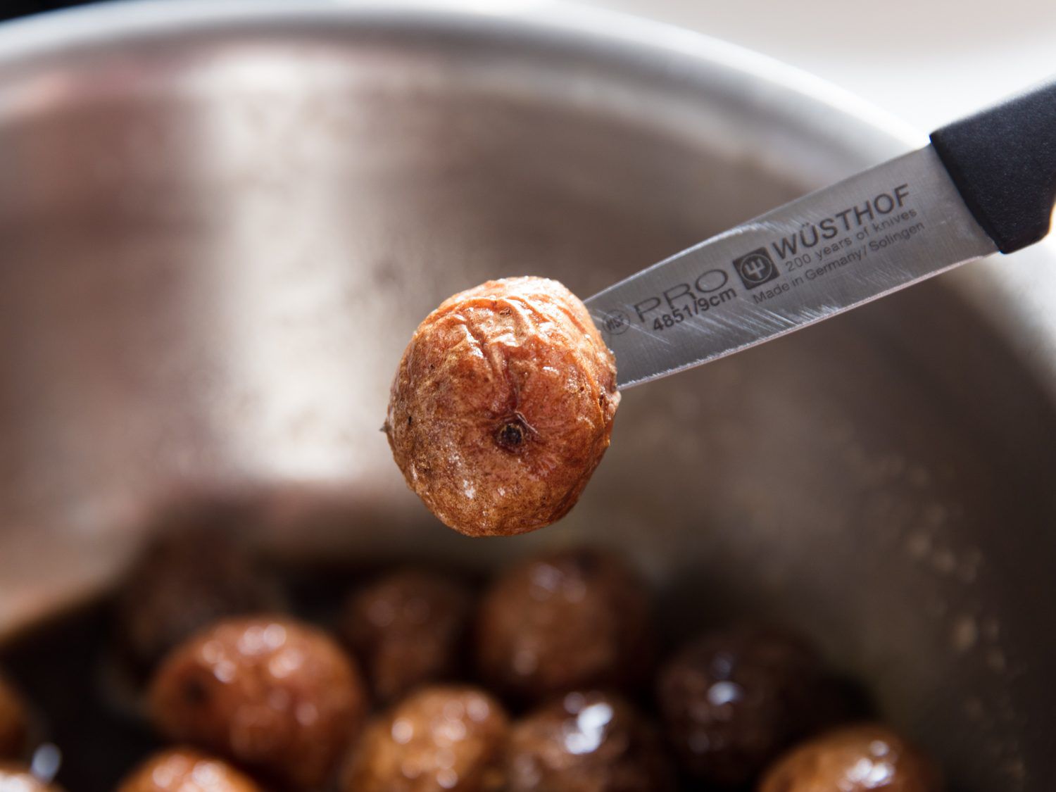 Testing potatoes for doneness with a paring knife.