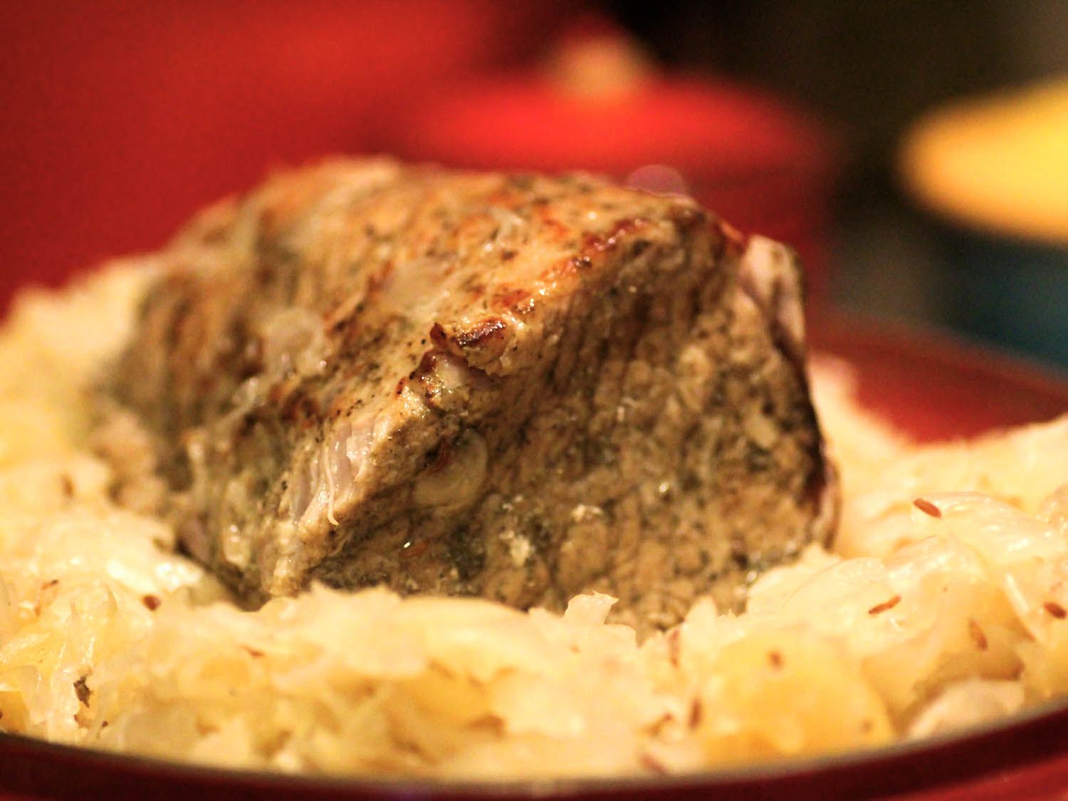 A pork roast on a platter , surrounded by sauerkraut.
