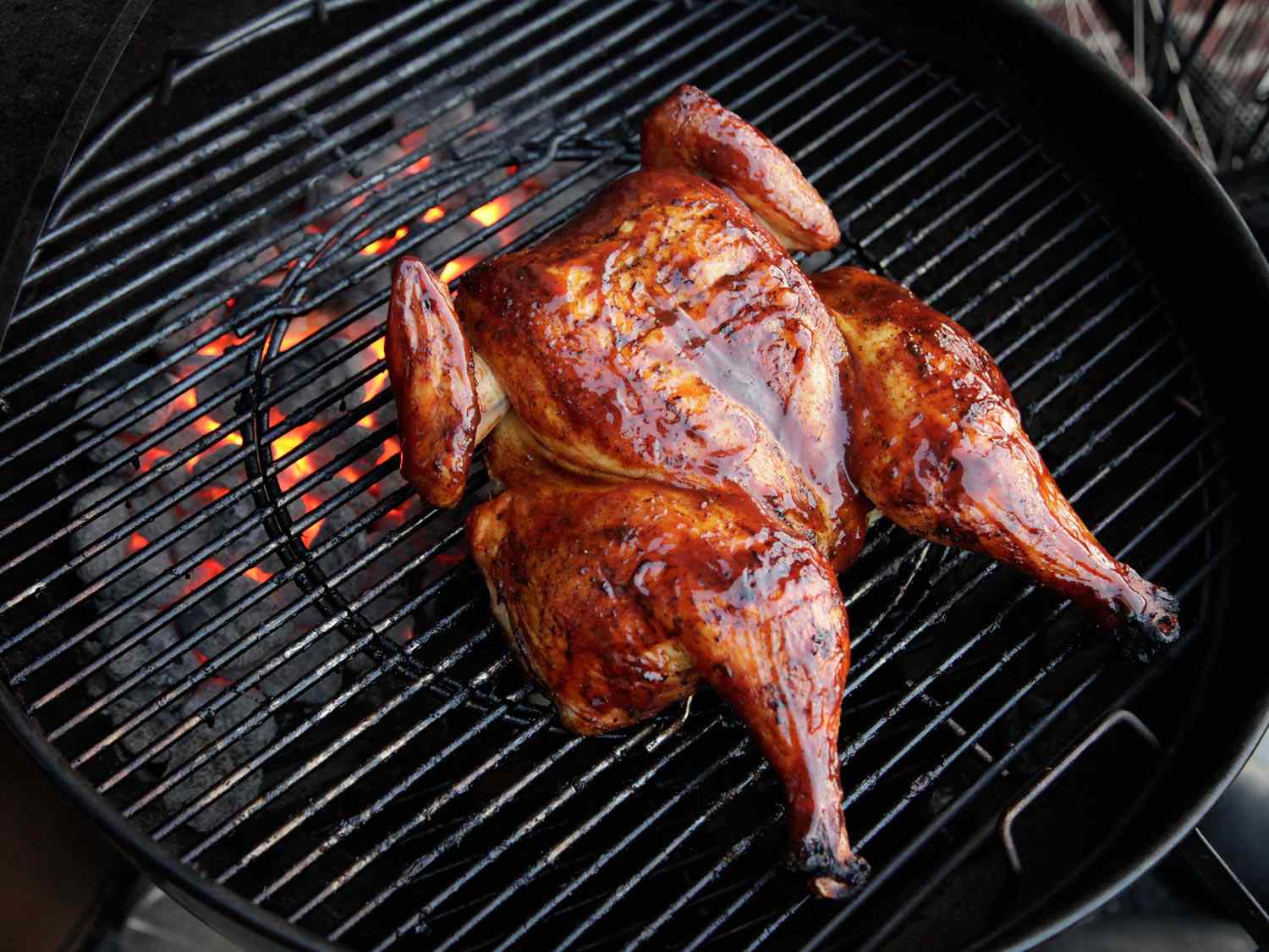 A whole barbecued chicken on a grill.
