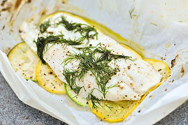Fish grilled in parchment, with sliced yellow and green summer squash and plenty of dill on top.