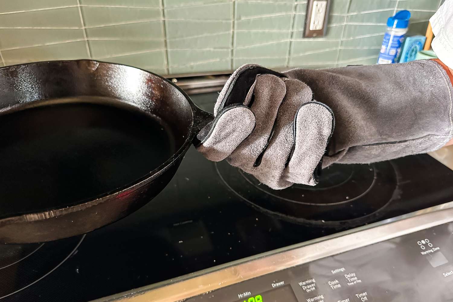 A person wears the Breeo Fire Pit Gloves while holding a pan