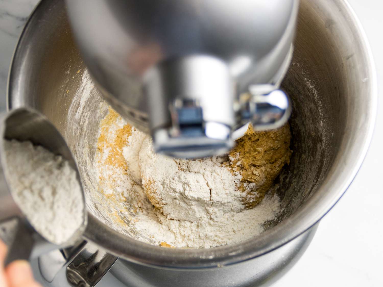Adding flour to stand mixer with dough