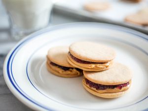 Closeup of PB&J sandwich cookies, stacked on a plate.
