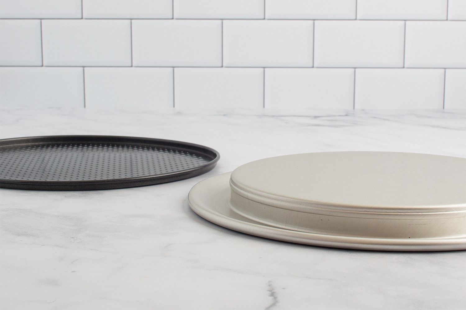 The bases of two springform pans on a marble kitchen countertop.