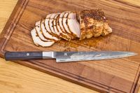 The Miyabi Koh 9.5 Inch Slicing Knife on a cutting board after slicing meat