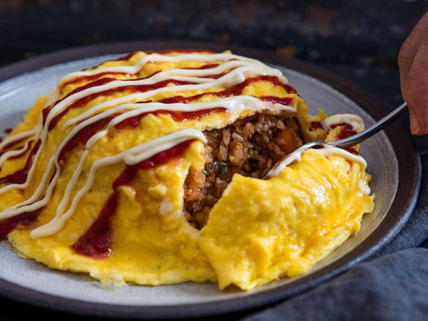 Cutting into finished dish of omurice with chicken and ketchup.