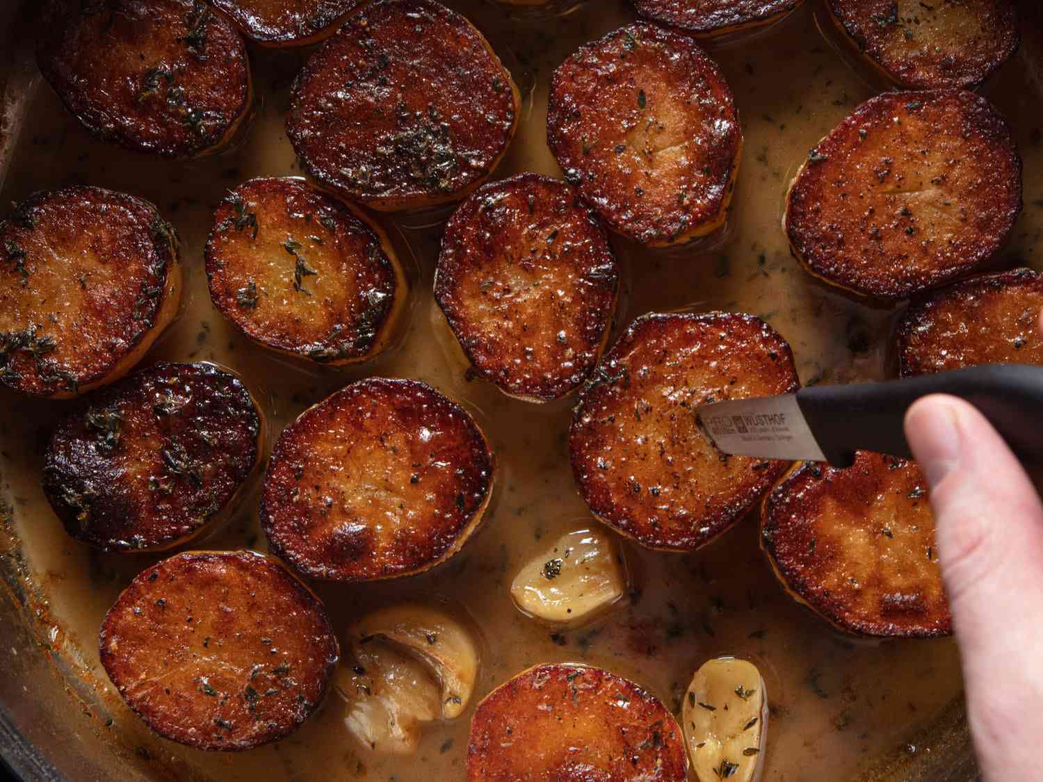 Testing doneness of potatoes with a paring knife.