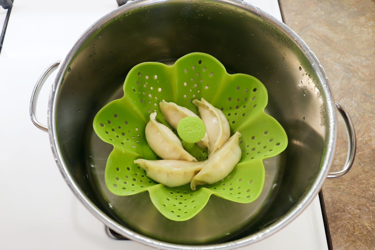 Dumplings cooking in a silicone steamer basket in a large pot.