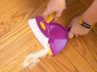 the cadet mini hand broom being used to sweep up rice