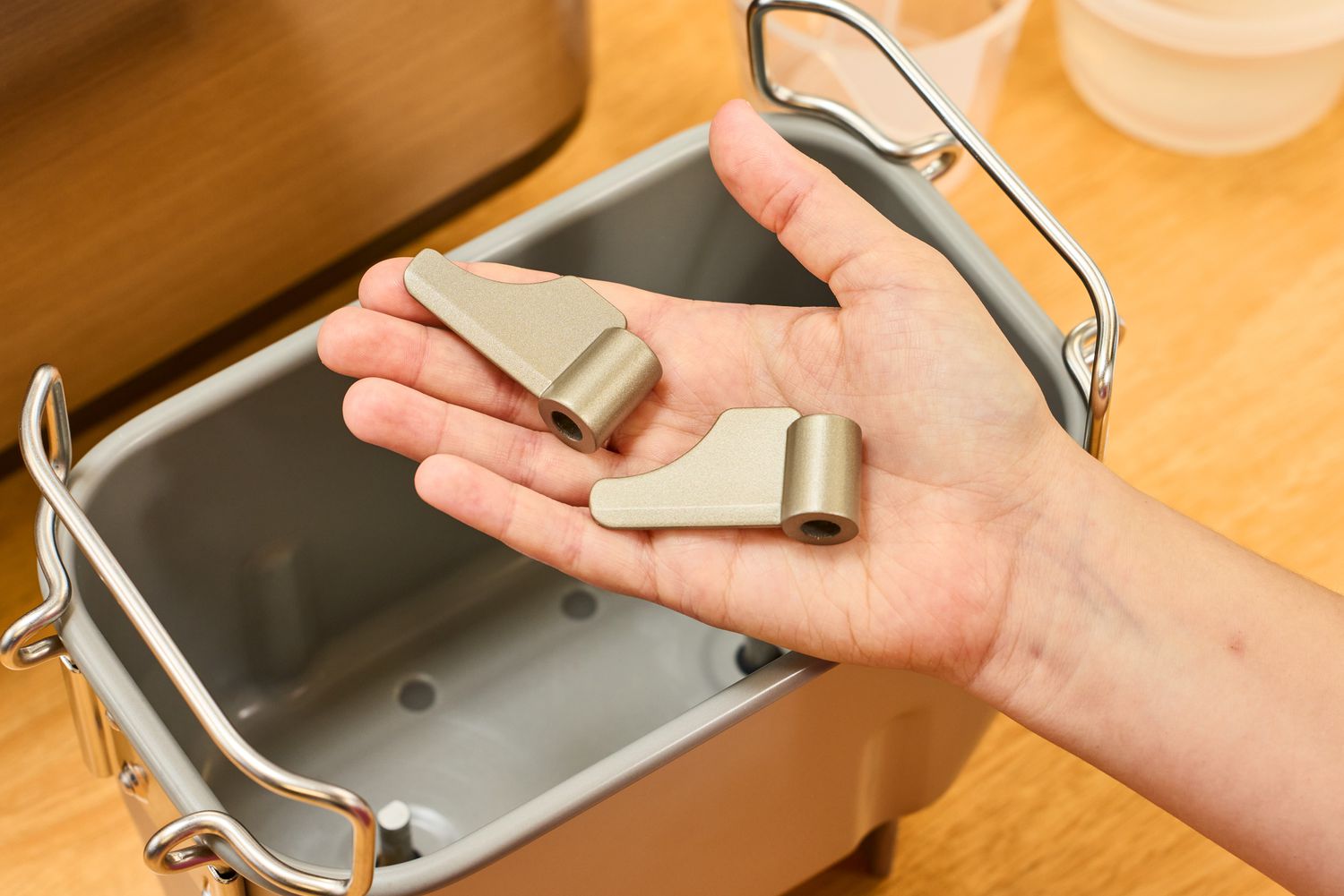 A hand holding parts to the Zojirushi Home Bakery Virtuoso Plus Bread Maker basket