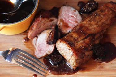 Sliced pan-roasted pork tenderloin next to bowl of bourbon fig glaze.