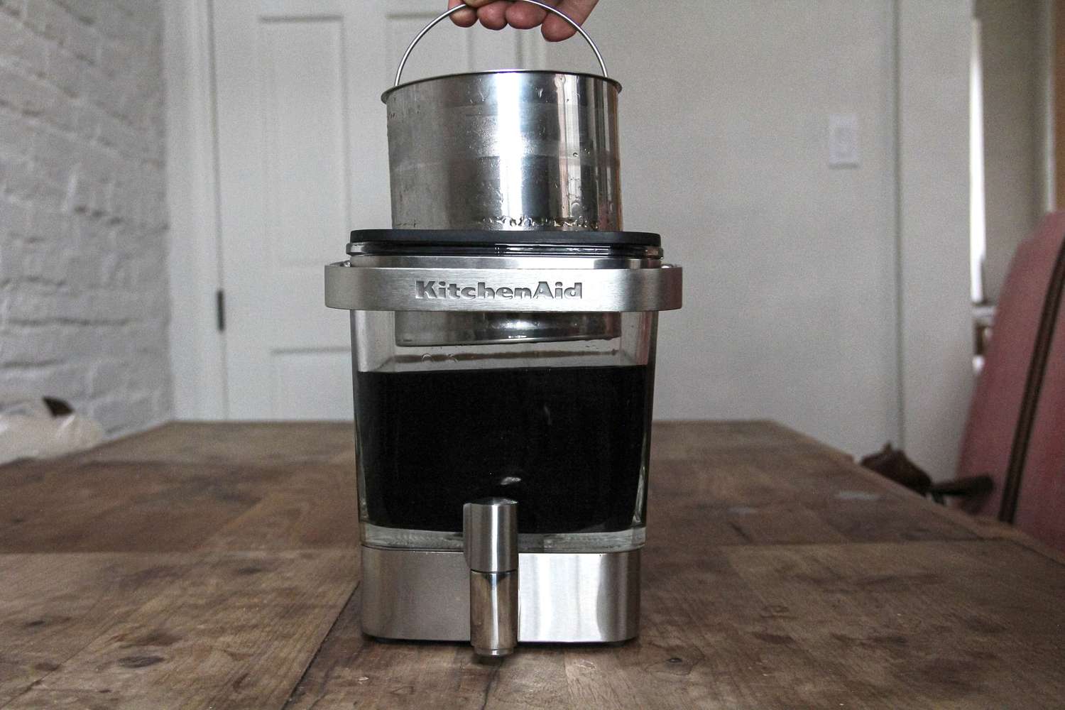 A person lifting the KitchenAid cold brewer maker's filter out of the carafe.