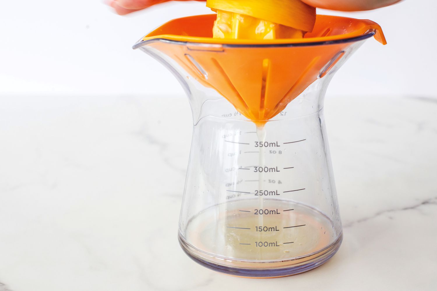 A person juicing a lemon into a countertop citrus juicer.