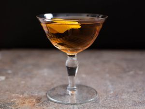 A martinez cocktail in a glass with a lemon twist. 