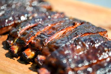 Closeup of barbecued apricot-glazed pork ribs on a wooden board