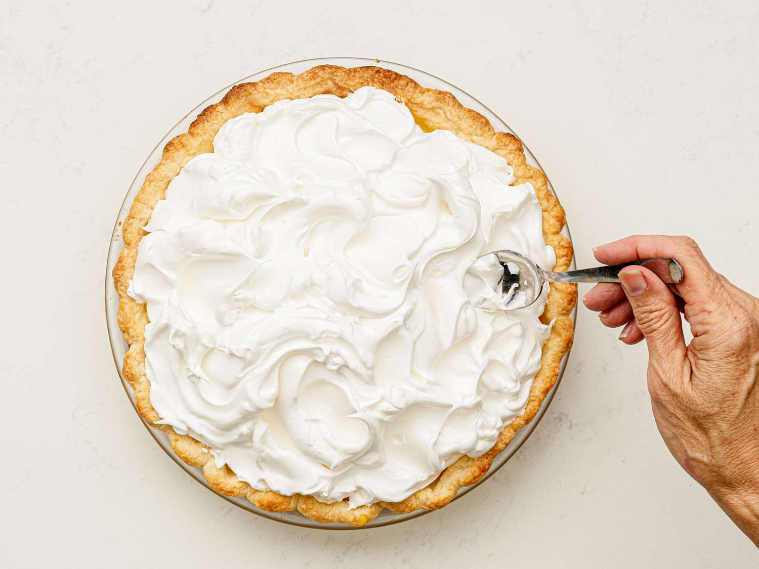Overhead view of using a spoon to make attractive swirls in the meringue topping.