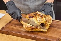 A person cuts a chicken with the Miyabi Koh 9.5 Inch Slicing Knife