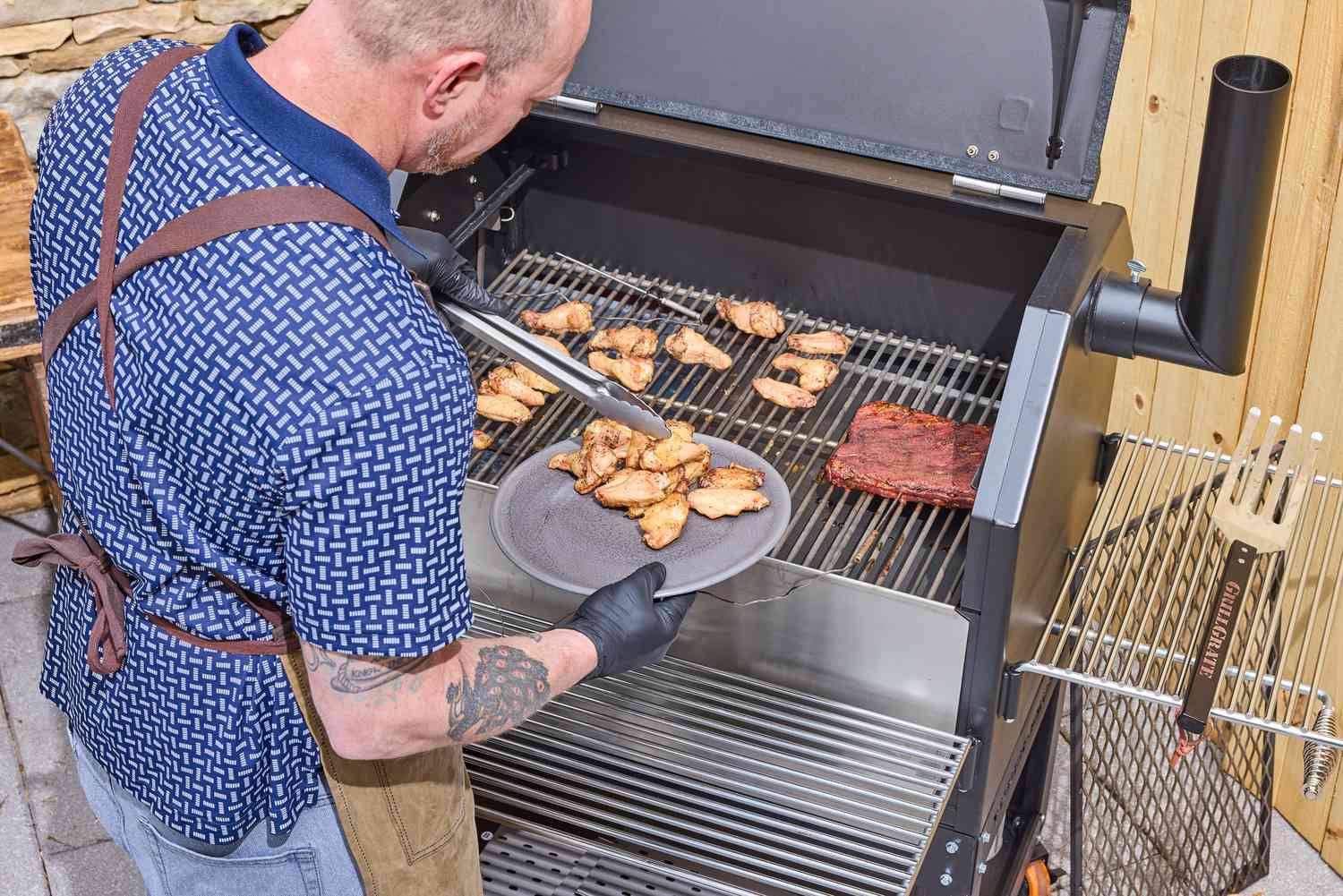 A person cooks chicken wings in the Yoder Smokers YS640S Pellet Grill