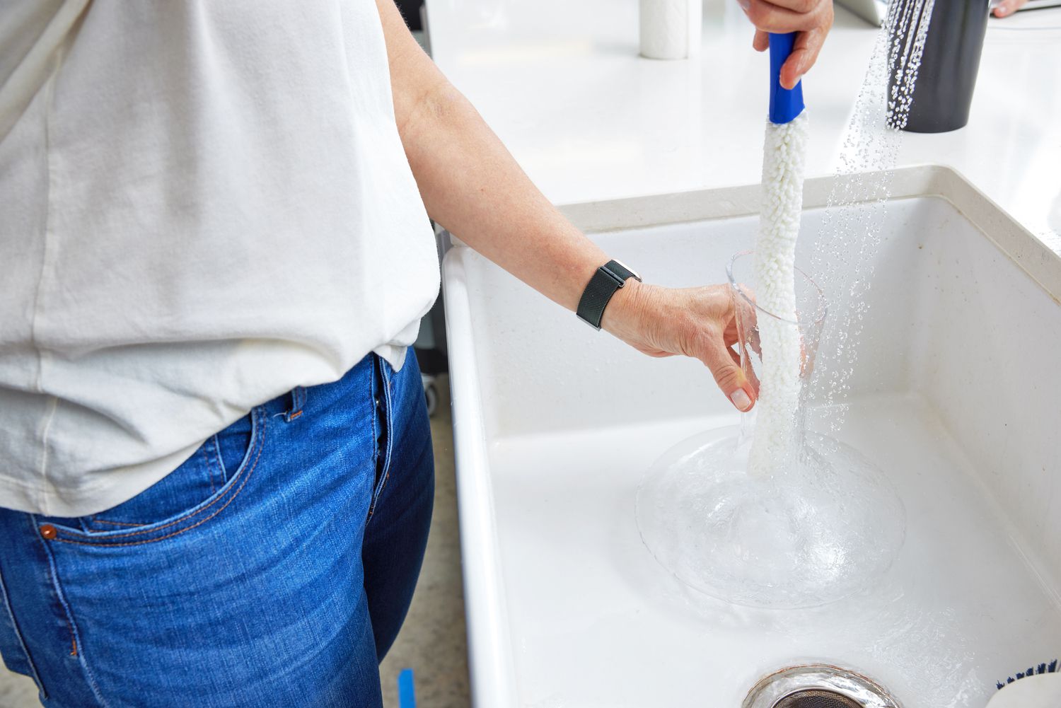 A wine decanter brush cleaning a wine decanter in a sink