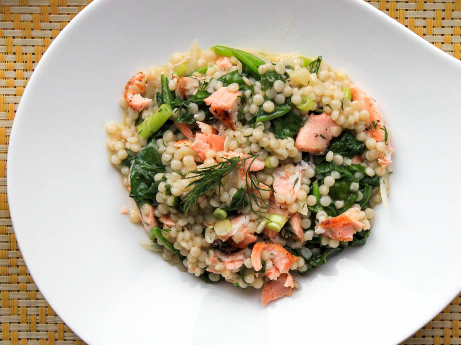 Warm couscous salad with salmon and dill, in a white dish