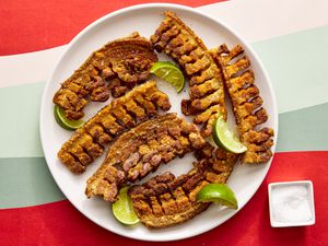 Overhead view of chicharrones on a plate with a small bowl of salt off to the side 