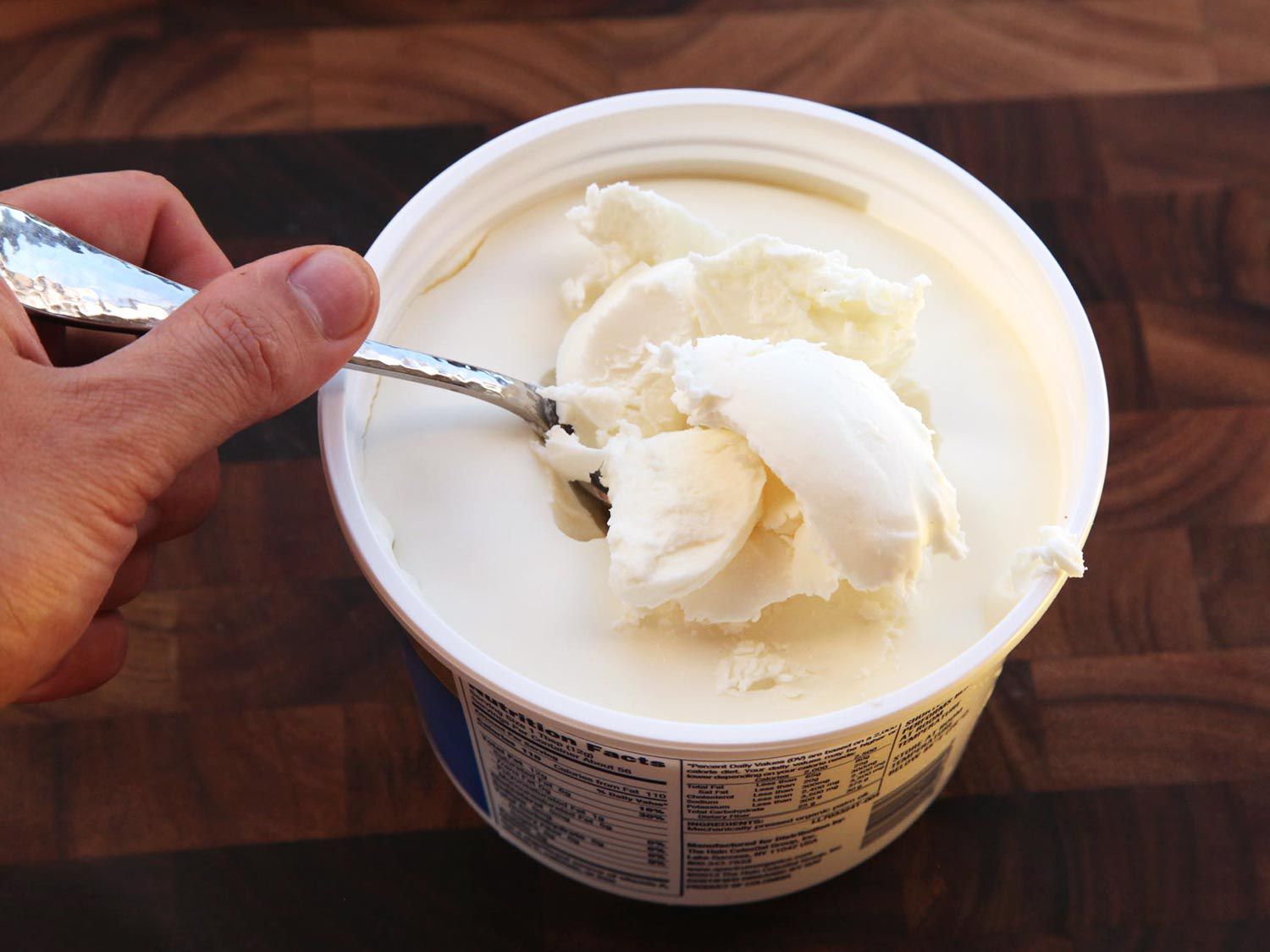 Author scooping vegetable shortening out of a container with a spoon.