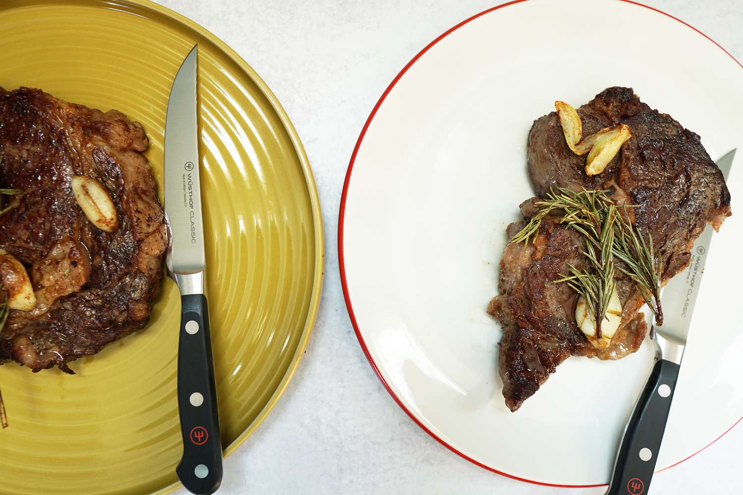 Two steaks on two dinnerware plates with knives