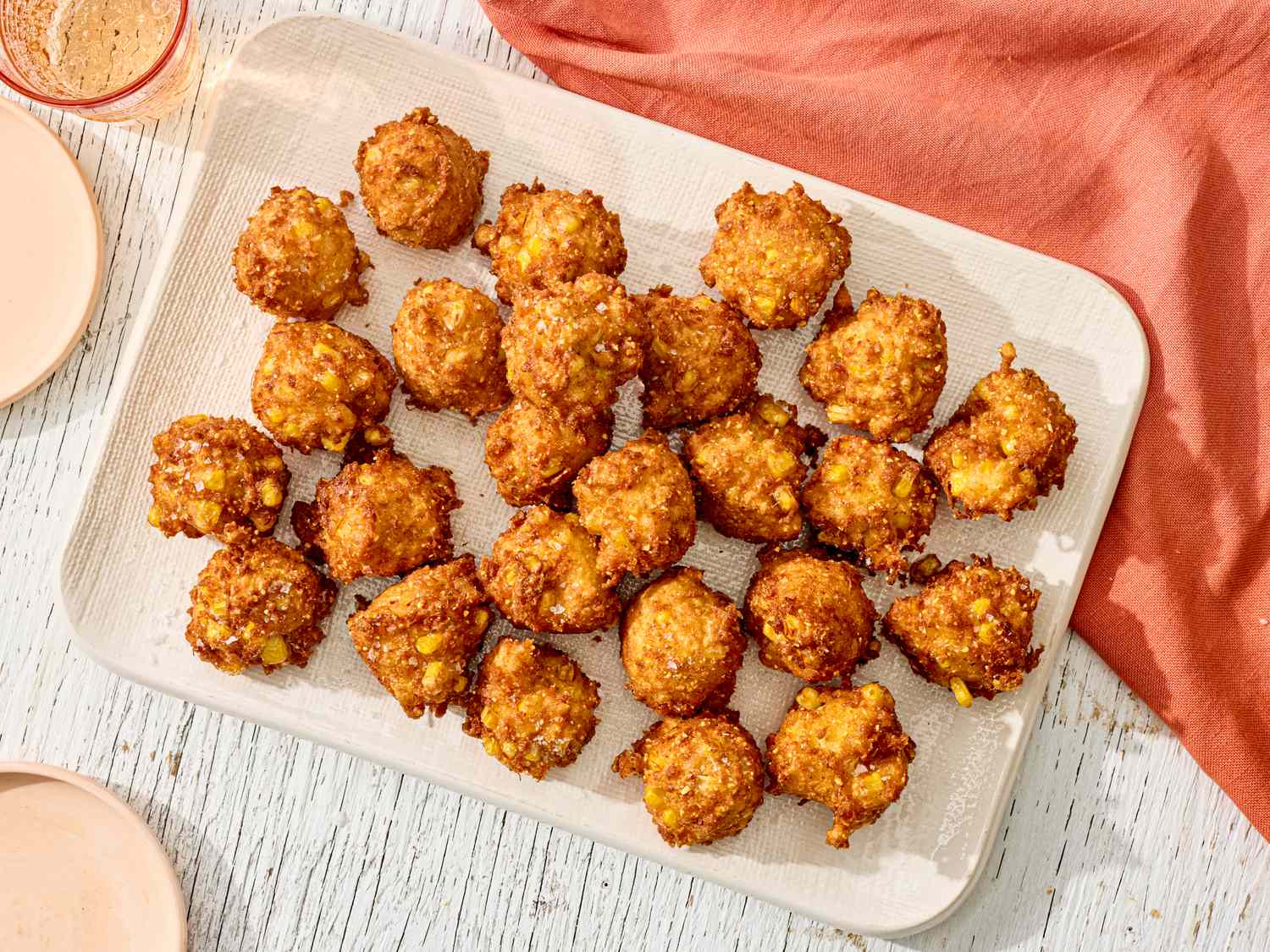 A tray of Southern corn fritters on a wooden board shot from above