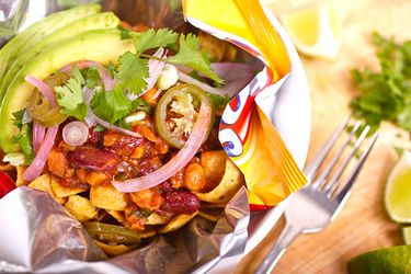 Closeup of a vegan Frito pie, garnished with avocado and cilantro.