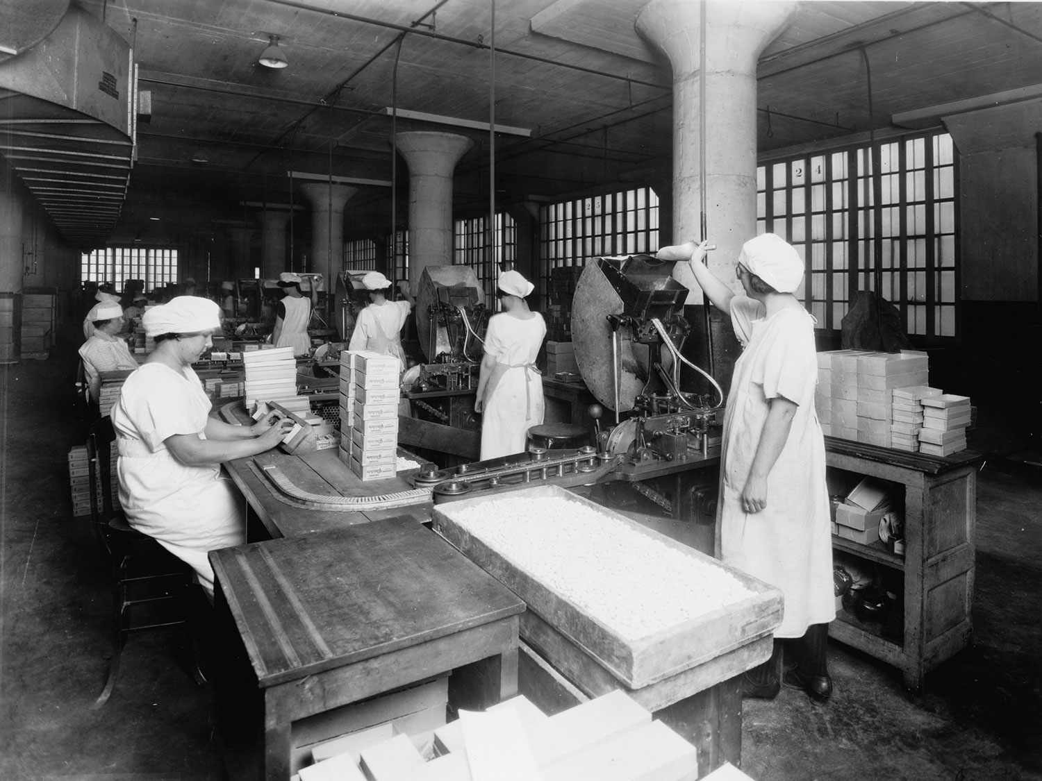 A black and white photo from a Chiclet's gum factory: A Chiclets production line.