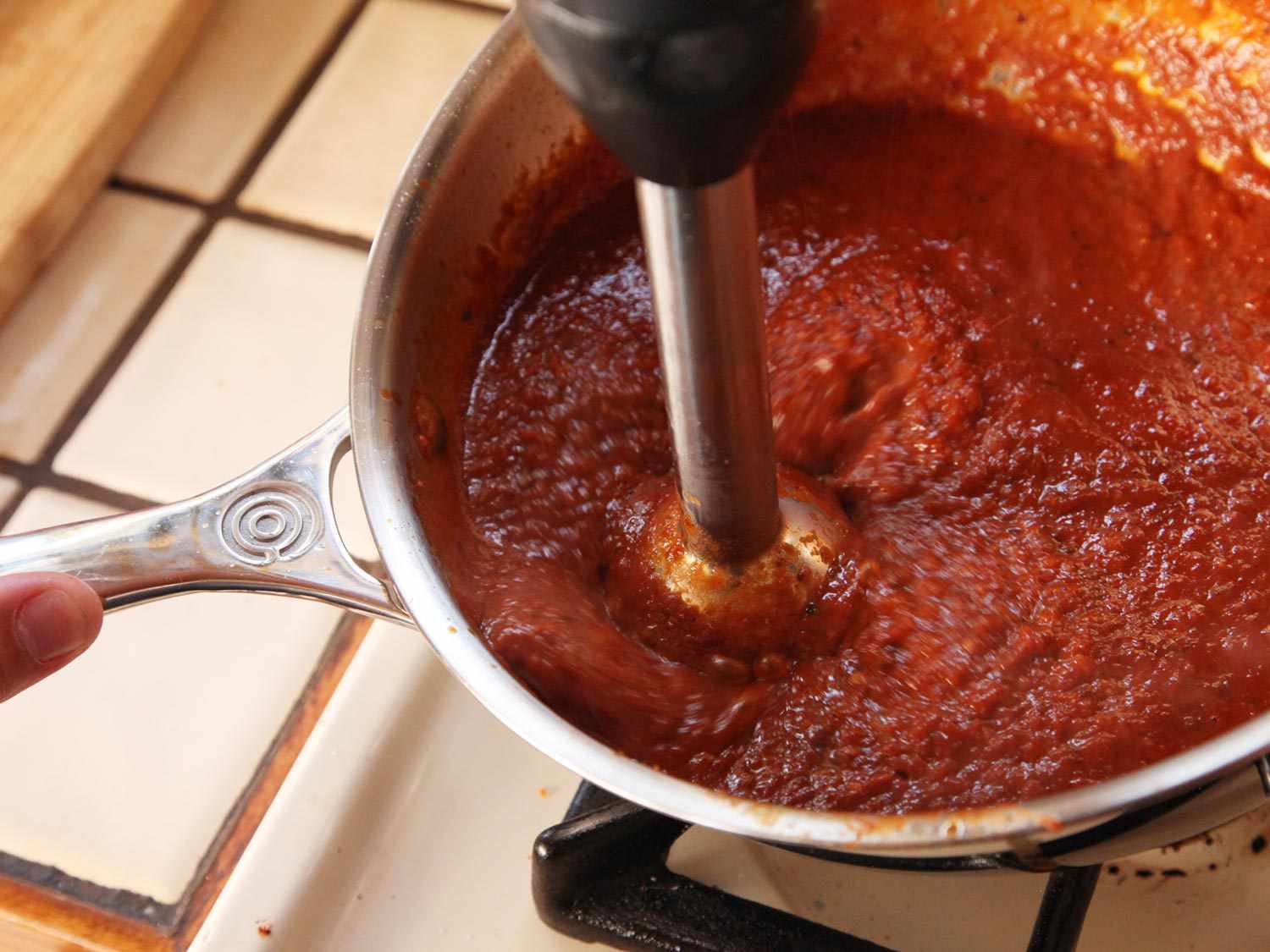 Pureeing a pot of tomato chile salsa for huevos rancheros.
