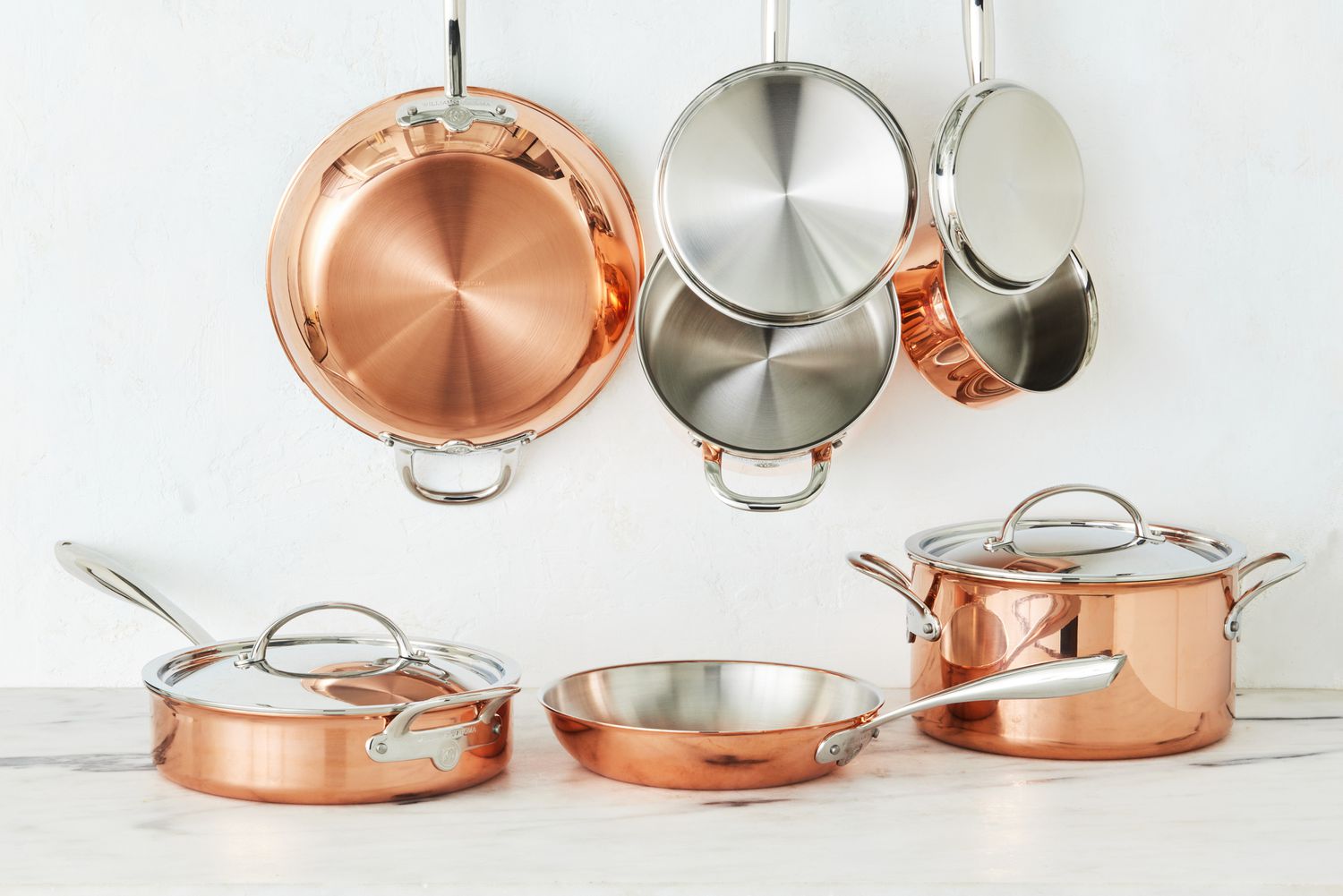 The Williams Sonoma Thermo-Clad Copper 10-Piece Cookware Set displayed in front of a white wall