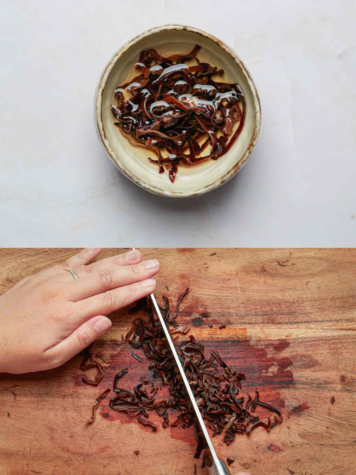 A bowl of marinated squid strips and a hand slicing squid on a wooden cutting board
