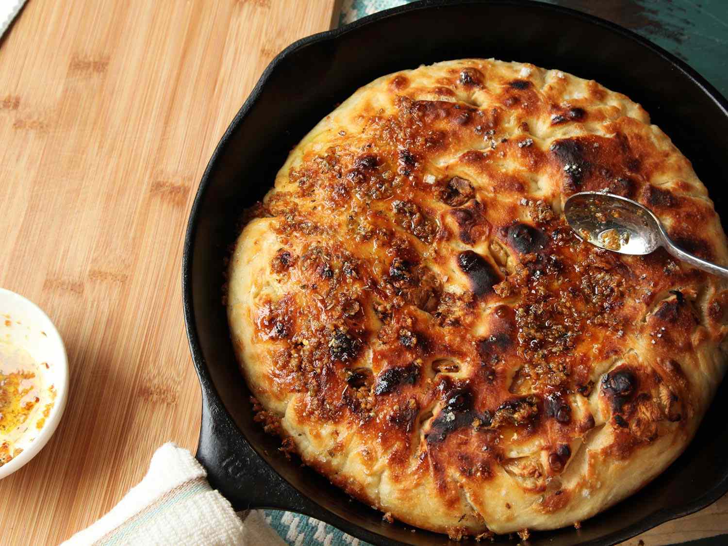 Spreading garlic butter over the top of no-knead garlic focaccia.