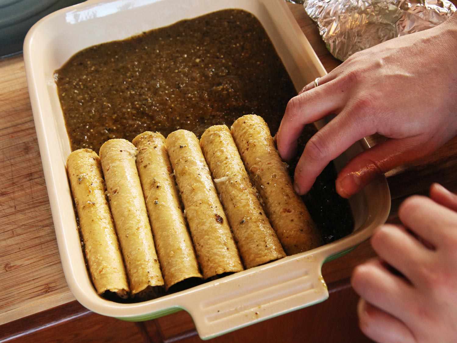 The filled and rolled tortillas are placed in the baking dish.