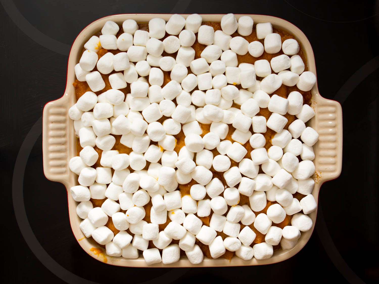 Overhead shot of mini marshmallows covering baking dish of mashed sweet potatoes 