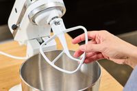 A person adds the mixer attachment to the KitchenAid Classic Plus Series 4.5 Quart Tilt-Head Stand Mixer