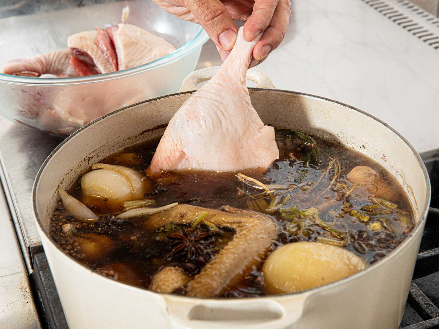 Overhead view of adding duck legs to broth