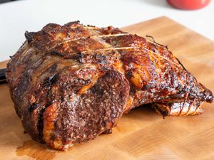 A whole cooked prime rib roast resting on a cutting board. 