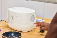 A person presses a button on the Cuckoo 6-Cup Micom Rice Cooker
