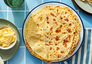 A plate of lefse flatbreads with butter on the side set on a tiled surface